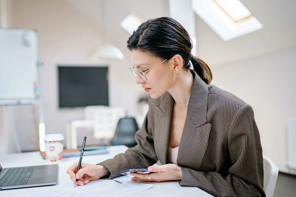 Professional woman writing notes while working in a contemporary office environment.