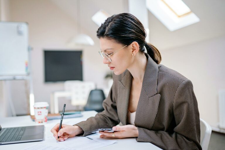 Professional woman writing notes while working in a contemporary office environment.