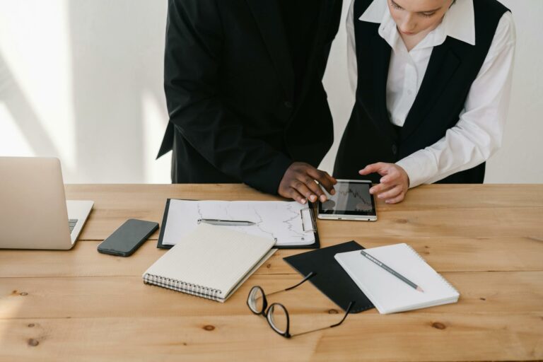Two professionals collaborating over charts and tablet in a modern office setting.